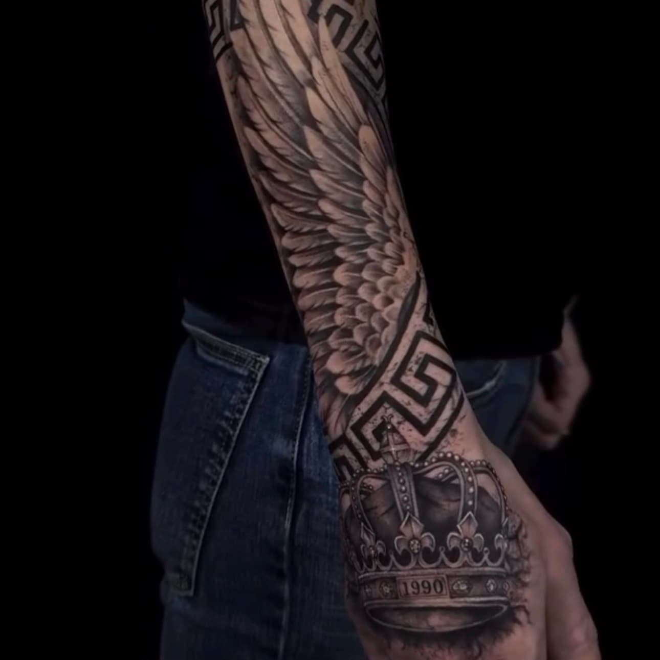 Realistic wings tattoo with greca and crown on the hand
